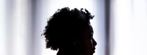 Vemos la cabeza de una mujer afro de perfil, lo vemos a contraluz, generando sombras en la imagen.